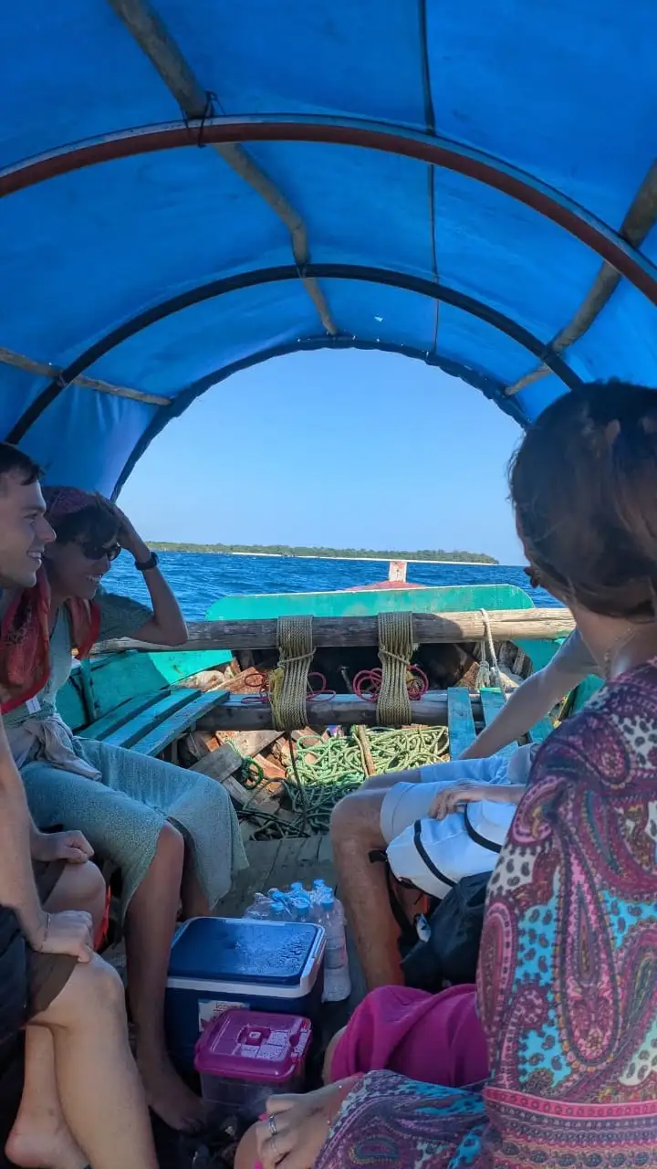 Guests sitting under the boat's blue canopy as it crosses to the sandbank.