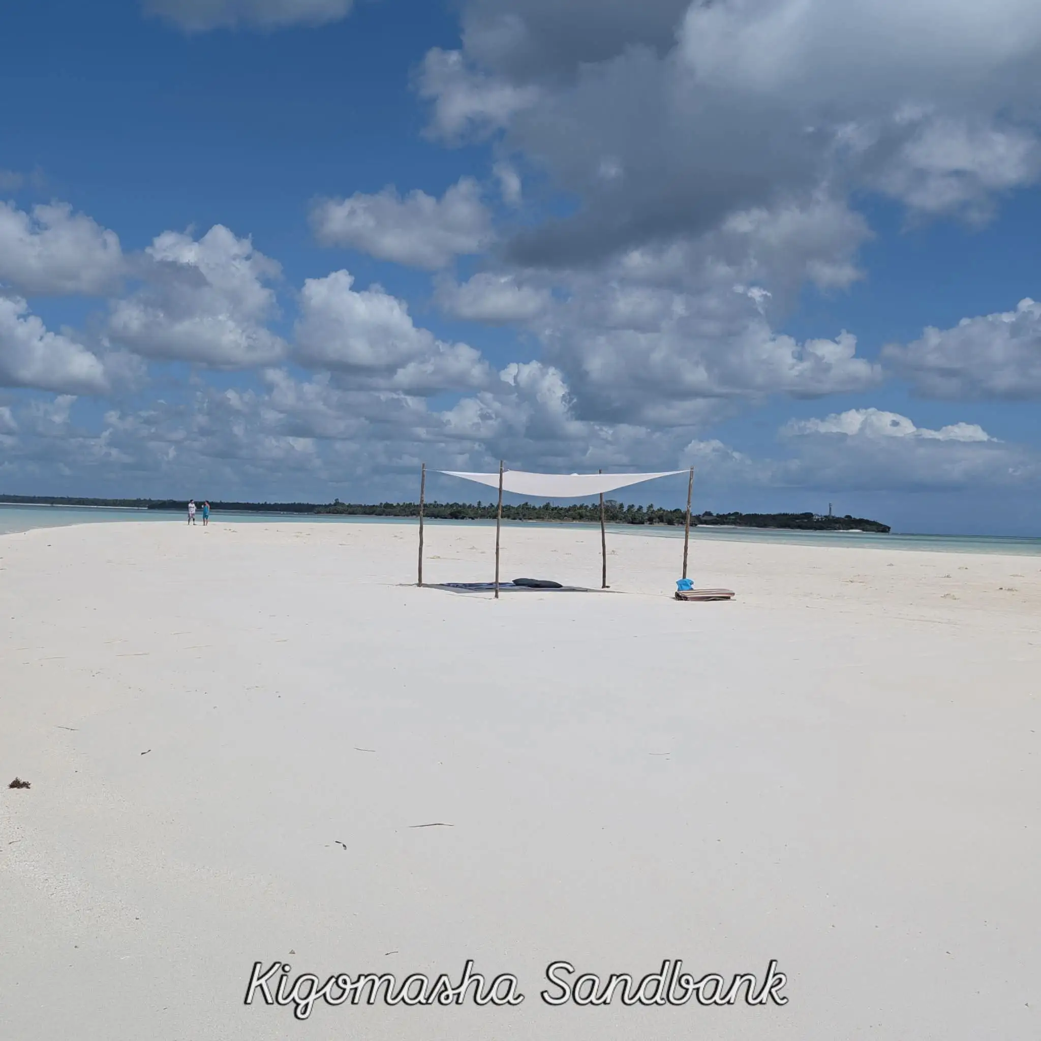 A sail-cloth sun shade pitched on the wide empty sand of Kigomasha sandbank.